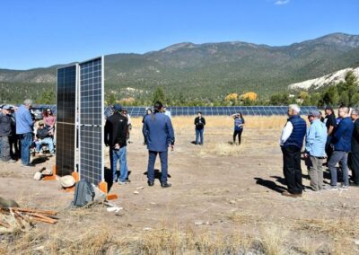 People on a field with solar panels and the mountains in the distance
