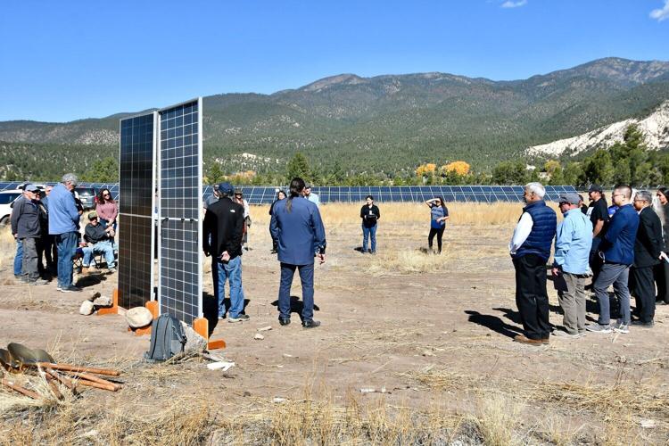 People on a field with solar panels and the mountains in the distance